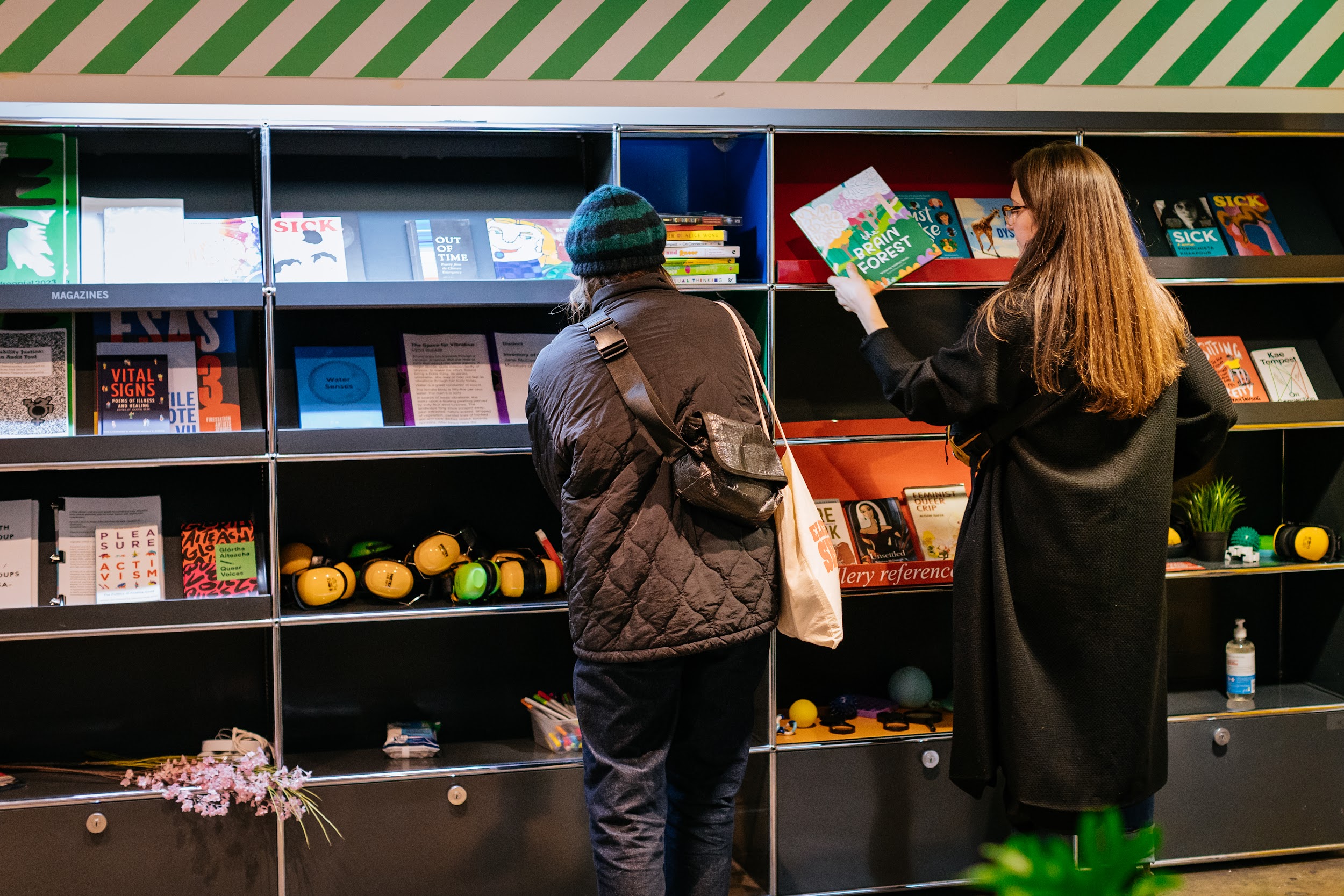 Two figures, seen from behind peruse the literature at the discovery station at the Disrupt festival in Project Art Centre.