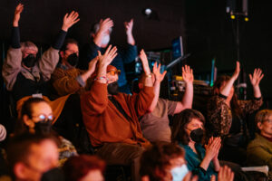 Disrupt audience hands up in applause for a show.